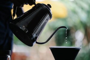 Svart vattenkanna häller droppande vatten i en skål